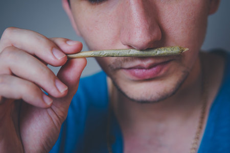 Close-up of adult man lights up with matches and smoking medical marijuana joint. Concept of herbal...