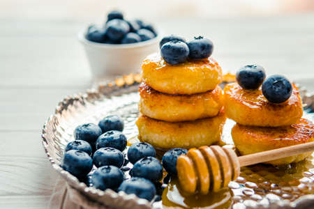 Homemade cheesecake with freshly picked juicy blueberries in the plate on wooden background, close up. blueberry background. Concept of healthy nutrition, organic food, breakfastの写真素材