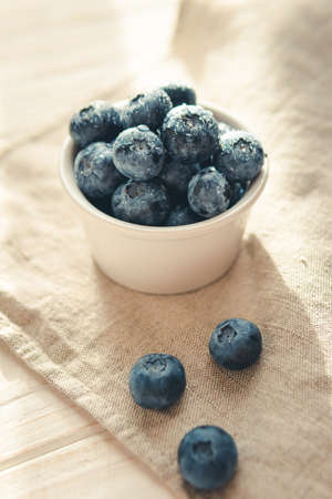 Freshly picked juicy blueberries in the bowl on wooden background, close up. blueberry background. Concept of healthy nutrition, organic food. Vegan and vegetarianの写真素材