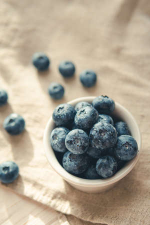 Freshly picked juicy blueberries in the bowl on wooden background, close up. blueberry background. Concept of healthy nutrition, organic food. Vegan and vegetarianの写真素材