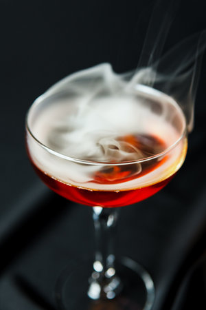 Alcoholic drink. A cocktail with whiskey or cognac with fire and smoke close-up, dark black background. Concept of elite alcohol and nightlife.の写真素材