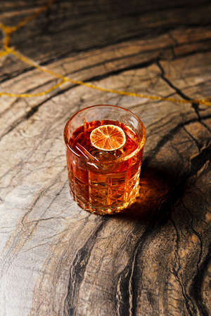 Alcoholic drink. A cocktail with whiskey or cognac on the table, close-up, dark background. Concept...