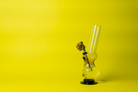 Marijuana bud and bong on yellow background, close up. Concept of herbal and alternative medicineの写真素材