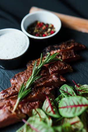 Sliced grilled steak medium rare served on black cutting board with vegetables. Delicious juicy meat in the restaurant menu. concept of cateringの写真素材