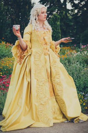 Portrait of blonde woman dressed in historical Baroque clothes with old fashion hairstyle, outdoors. golden color dress. Luxurious medieval dressの写真素材