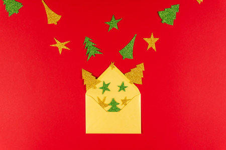 New Year red background with golden envelope and paper star and tree, flat lay. Concept of greeting card for holidaysの写真素材