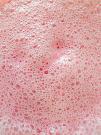 Texture of Fresh Milkshake or smoothie in glass with strawberries top view, close up. Concept of...