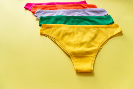 Set of colorful underpants on yellow background, close up. Cotton panties. women's underwear. top view.の写真素材