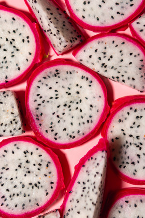 Slices of fresh white pitaya or dragon fruit on pink background, flat lay. Concept of exotic tropical and vegan food.の写真素材