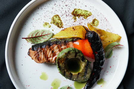 Grilled salmon fish fillet with vegetables and avocado on the plate, close up. Delicious food in the...