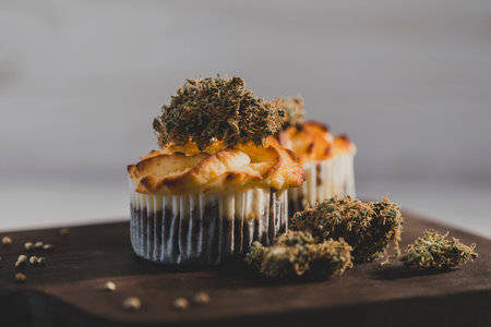 Cake with medical marijuana buds on wooden cutting board, close up. Alternative dessert and medicinal herbs conceptsの写真素材