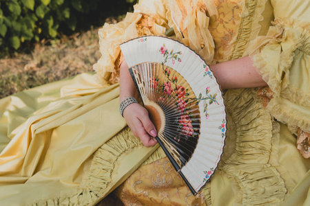 Luxurious medieval hand fan in the female hand, close-up. Baroque accessory. Selective focusの写真素材