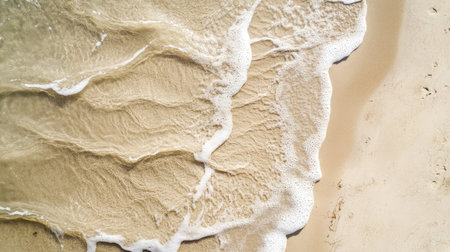 Natural flow patterns in beige sand, shaped by retreating seawater, photographed from aboveの素材