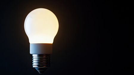 Close-up of glowing LED bulb isolated on black background, highlighting modern energy-efficient lighting technology with sharp contrastの素材