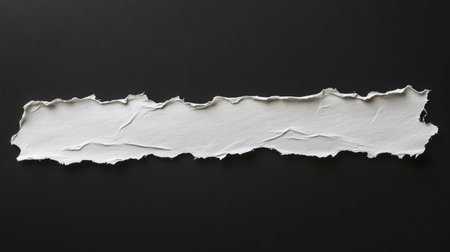 Horizontal strip of paper with uneven torn edges, isolated on black background, showcasing texture and fibrous paper strandsの素材