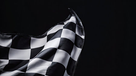 Dynamic shot of a racing checkered flag fluttering in the air, set against a deep black backdropの素材