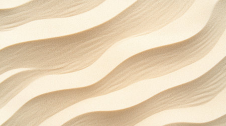 Top-down view of beige sand with smooth curved patterns created by gentle ocean wavesの素材