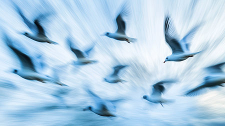 A flock of birds in flight against a blue sky, captured with dynamic motion blur to emphasize their synchronized movement.の素材