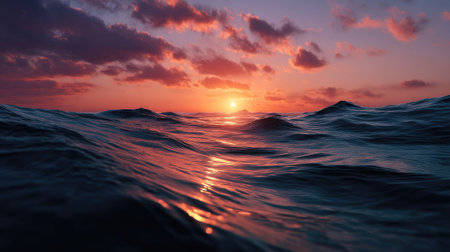 The ocean glowing in orange hues, with gentle waves reflecting the vibrant sunset sky, creating a calm and romantic atmosphereの素材