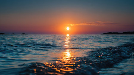 Sunset casting an orange glow across the horizon, where the sea meets the sky, reflecting beautifully on the water's surfaceの素材