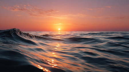 The ocean glowing in shades of orange, with a soft breeze creating gentle ripples on the surface as the sunset paints the skyの素材