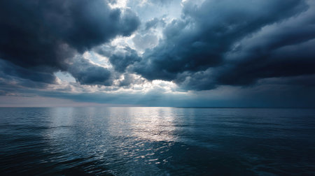 The horizon of the calm sea under a dramatic sky filled with dark storm clouds, creating a powerful natural sceneの素材
