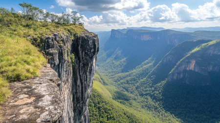 Rugged cliff edge with layered stone formations, towering above green mountains and deep valleysの素材