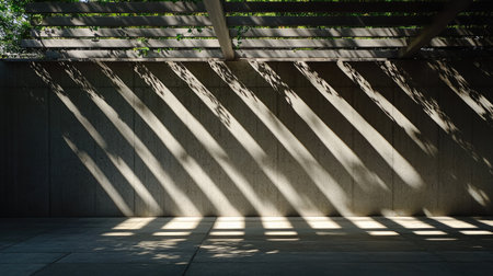 Sunlight breaking through gaps in a pergola, forming striped shadows on the concrete wall of an outdoor patioの素材