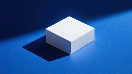 Small white box casting sharp shadows on a rich blue background, ideal for product mockup or branding conceptの素材