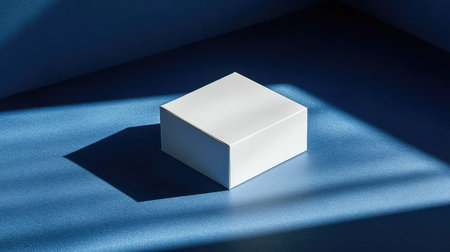 Small white box casting sharp shadows on a rich blue background, ideal for product mockup or branding conceptの素材