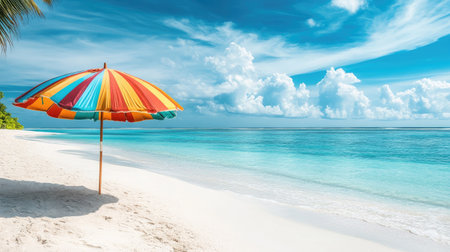 A close-up of a beach umbrella with colorful stripes, against a bright blue sky and a serene beach setting.の素材