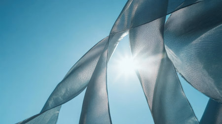 A close-up shot of a beach umbrella's fabric, with a clear blue sky and the sun shining through.の素材