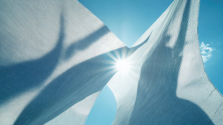 A close-up shot of a beach umbrella's fabric, with a clear blue sky and the sun shining through.の素材