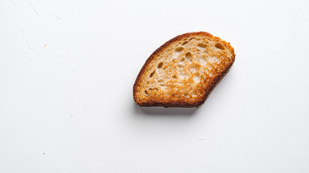 Single piece of toasted bread with even browning, resting on a clean white surface with minimalistic lightingの素材