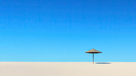 A solitary beach umbrella casting a shadow on the sand under the clear blue sky, evoking a peaceful vibe.の素材