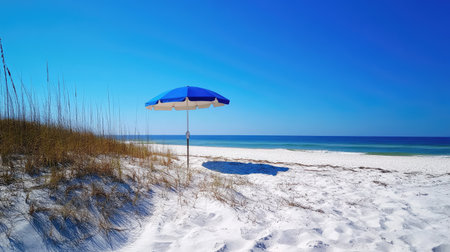 A beach umbrella set up in the sand, with a bright blue sky and no clouds in sight, perfect for a beach day.の素材