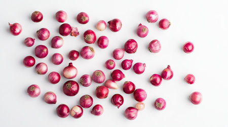 A scattered arrangement of small red onions, showing their varying textures and natural beauty on a clean white background.の素材