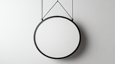 A round signboard mockup with a white background, suspended from a sleek black metal bracketの素材