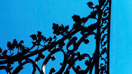 Classic black iron street lamp with intricate detailing, silhouetted against a vibrant blue skyの素材