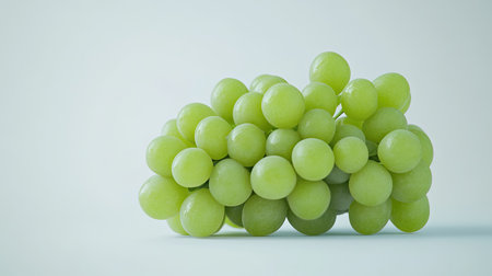 A pristine bunch of green grapes with smooth skin and vibrant color, isolated on a plain white background.の素材