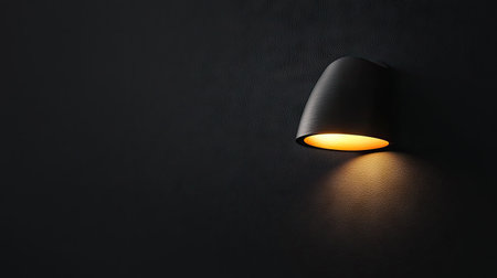 A dramatic close-up of a glowing wall lamp against a pitch-black background.の素材