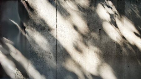 Dappled sunlight creating organic, shifting patterns of shadow on a weathered outdoor concrete wallの素材