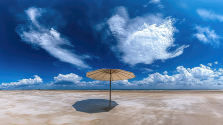 A wide-angle view of a beach umbrella on a deserted beach with the expansive blue sky overhead.の素材