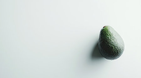 A fresh avocado placed on a white background, showcasing its round shape and rich green color against a minimal backdropの素材