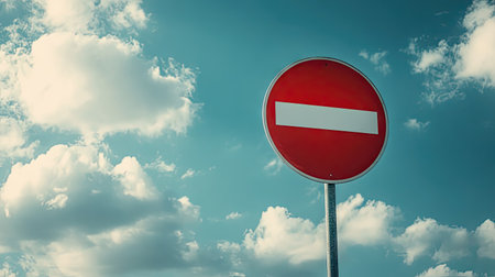 A striking red prohibition sign stands tall against a serene sky filled with fluffy clouds, embodying the essence of rules, limitations, and urban safety.の素材