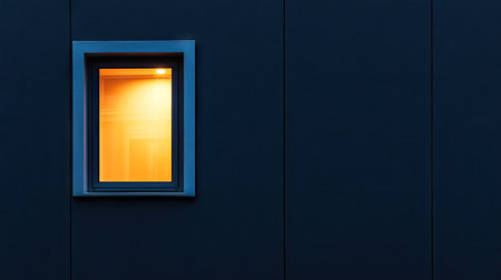 A captivating image of an illuminated window set against a dark wall, highlighting the interplay of light and shadow. The contrasting colors create a serene urban atmosphere.の素材