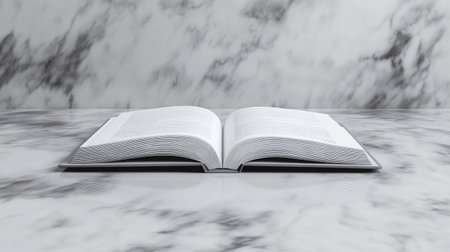 A single open book on a marble tabletop, with a soft reflection visible beneath it.の素材