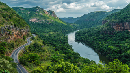 A winding mountain highway overlooking a wide river surrounded by lush forests and steep cliffsの素材