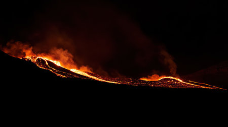 A dramatic night scene of a volcano erupting with fiery lava flows illuminating the dark landscapeの素材