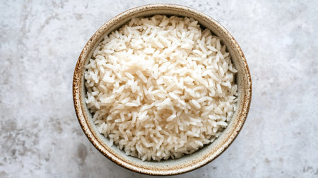 A top-down view of a bowl filled with soft white rice, neatly arranged on a clean, minimalistic background.の素材